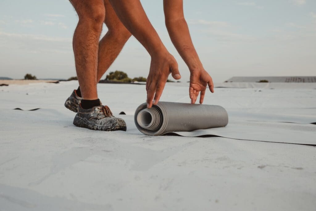flat roof repair Worker applies pvc membrane roller on roof very carefully