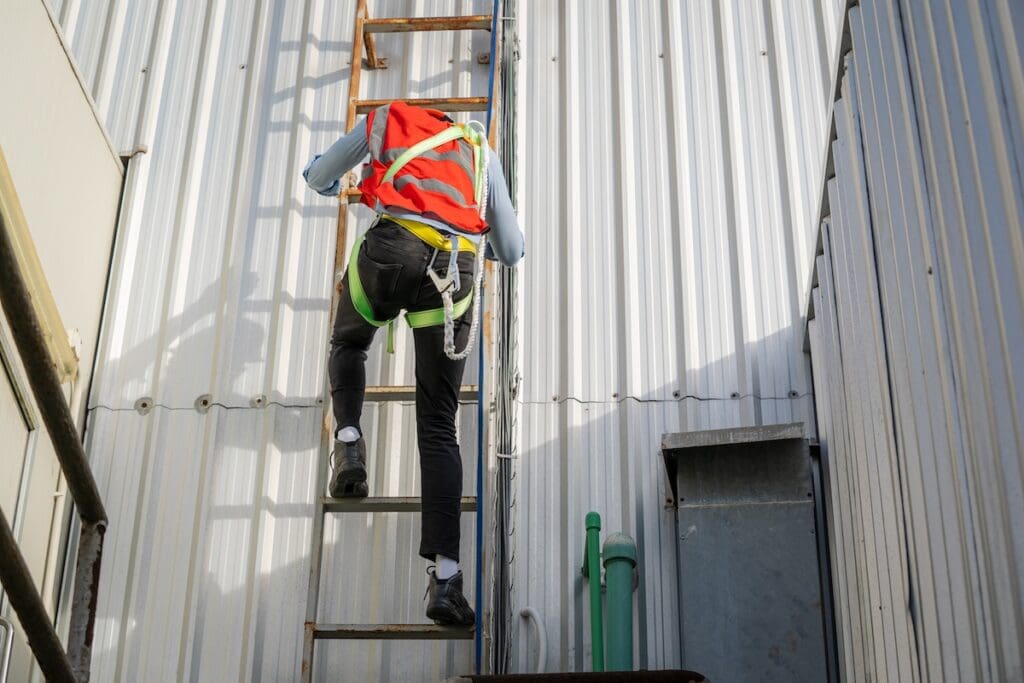 commercial roof inspection Construction worker wearing safety harness belt during working on roof structure of building on construction site.