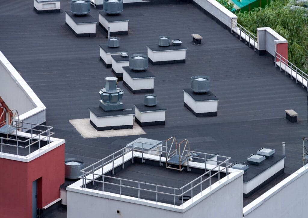 single ply membrane roof Top view flat roof with air conditioners and hydro insulation membranes on top of a modern apartment building summer day.