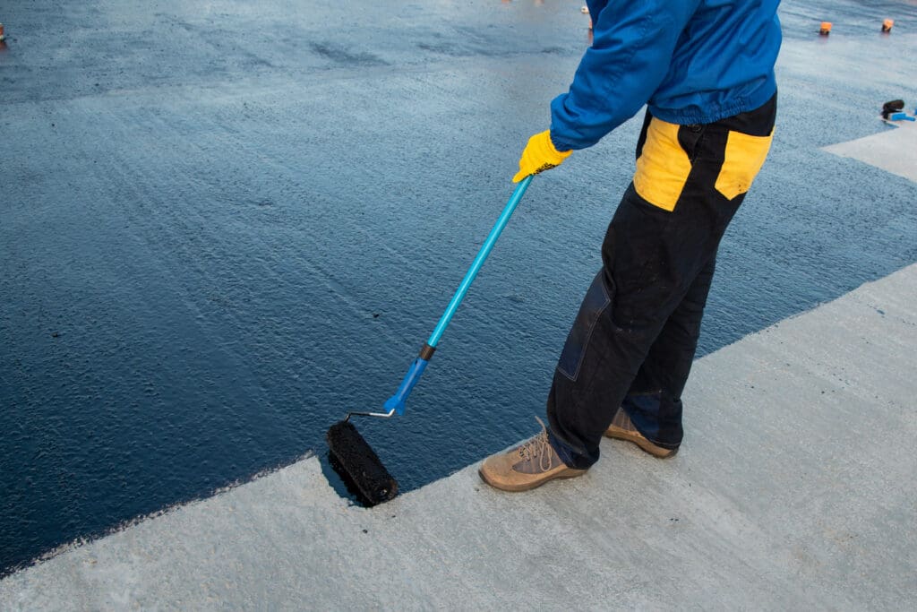 roof coating Waterproofing coating. Worker applies bitumen mastic on the foundation. Roofer cover the rooftop polymer modified bitumen waterproofing primer, with a roller brush.