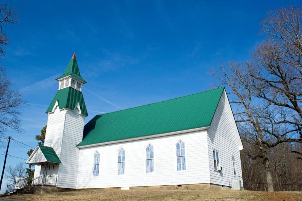 green metallic church roof blue sky white siding