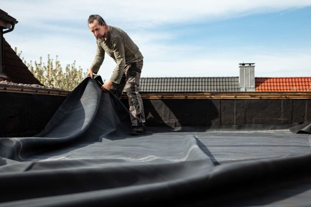 rubber roofing worker extending membrane on top of flat roof