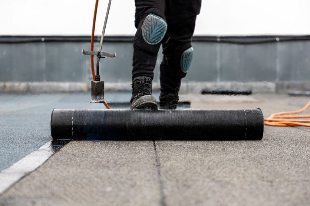 rubber roofing worker unrolling membrane on top of flat roof