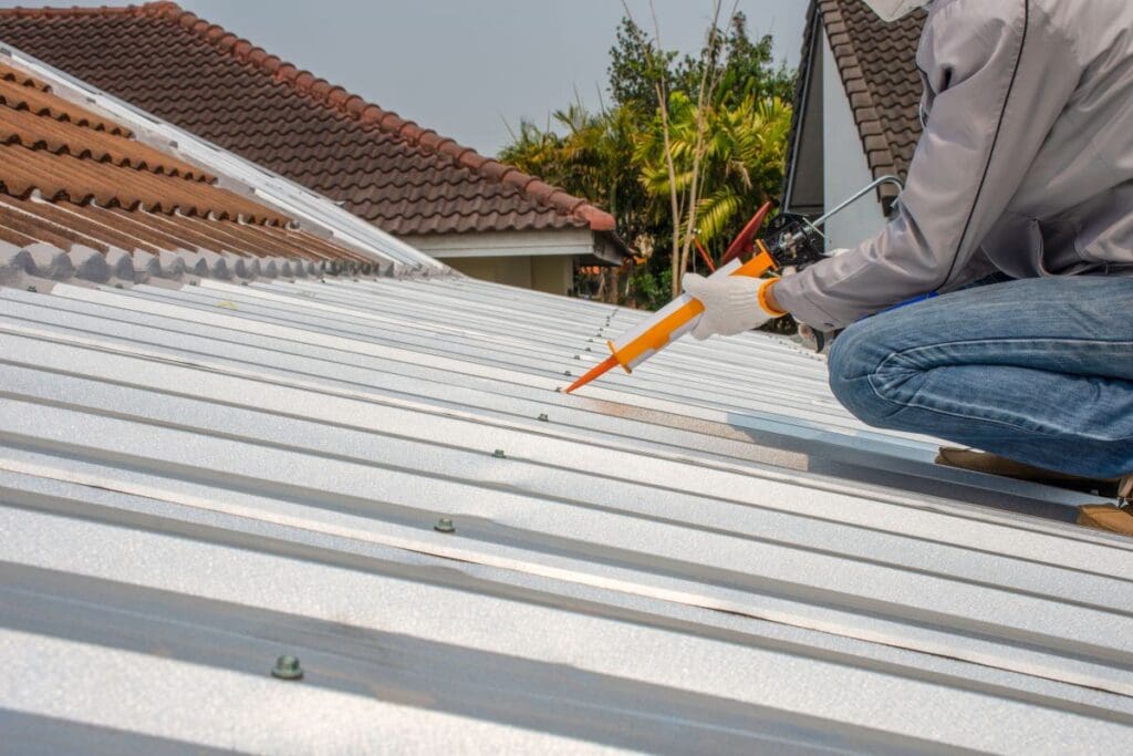 commercial roof preventative maintenance worker using sealant on metallic roof