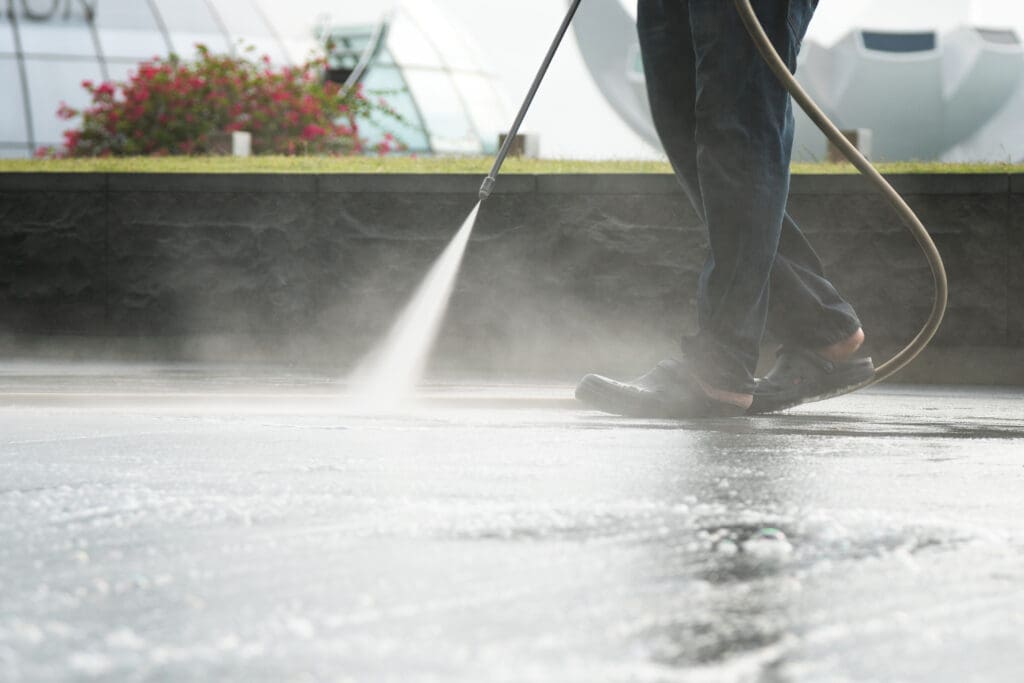 commercial roof coating cost worker using pressure hose to clean roof