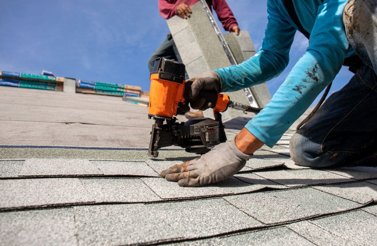 guy installing grey shingles roof