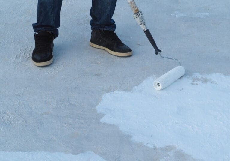 Man applies waterproof and thermal insulation of a roof from rain and sun.