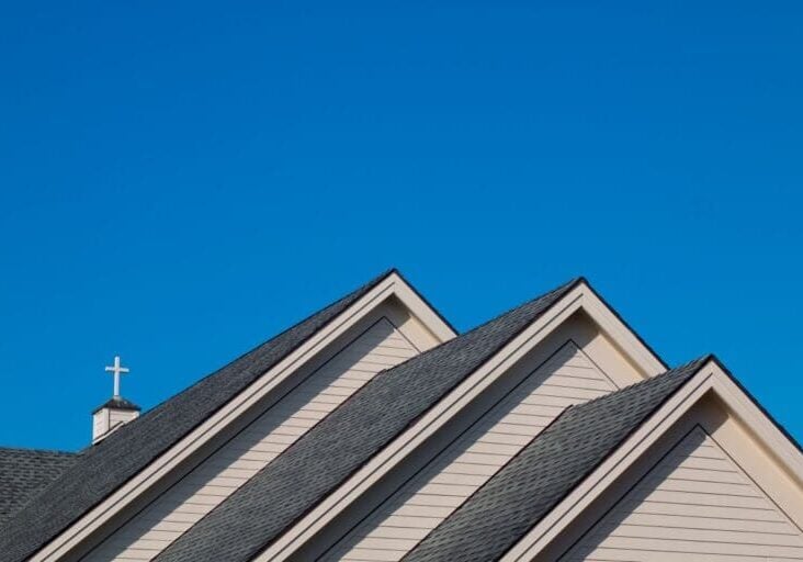 church roof blue sky white siding and charcoal shingles cross