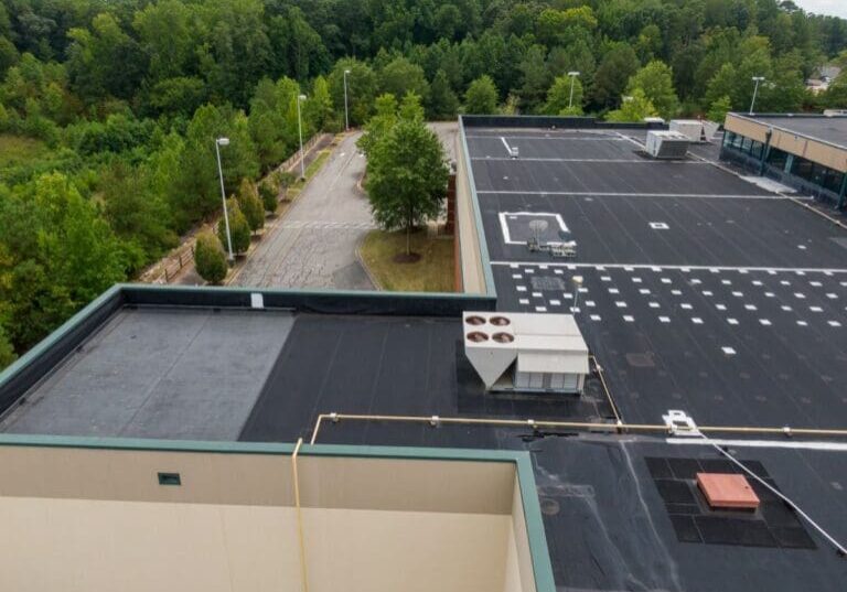 epdm roofing sealant commercial building surrounded by pine trees drone inspection